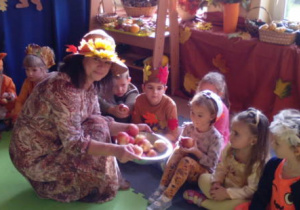 Pani Jesień częstuje dzieci jabłuszkami.